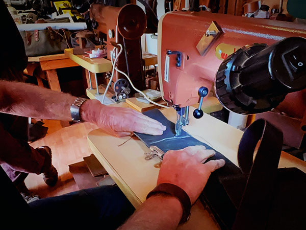 Worker sews leather with a leather sewing machine